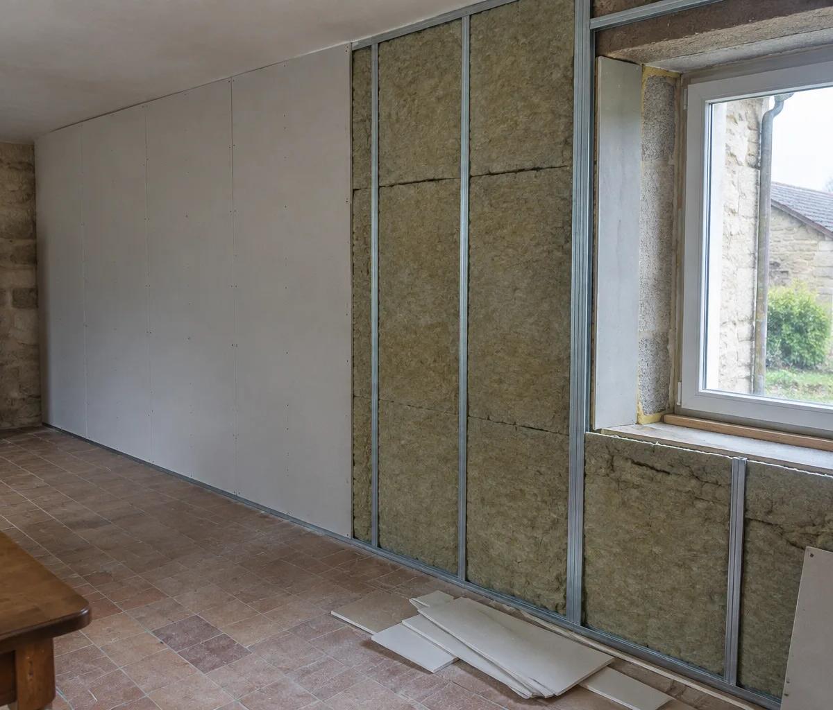Mur extérieur en cours d'isolation par l'intérieur : ossature métallique, laine minérale et plaques de plâtre